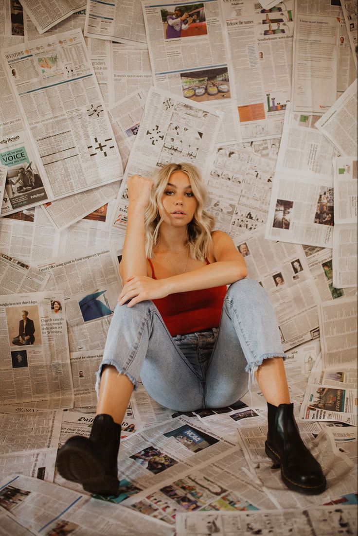 a woman sitting on top of a pile of newspapers