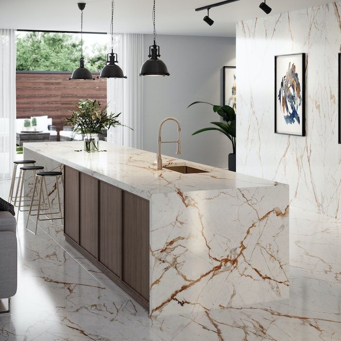 a kitchen with marble counter tops and bar stools next to a couch in the living room