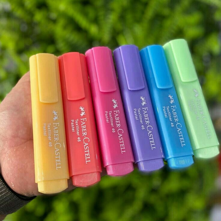 a person is holding five different colored pens