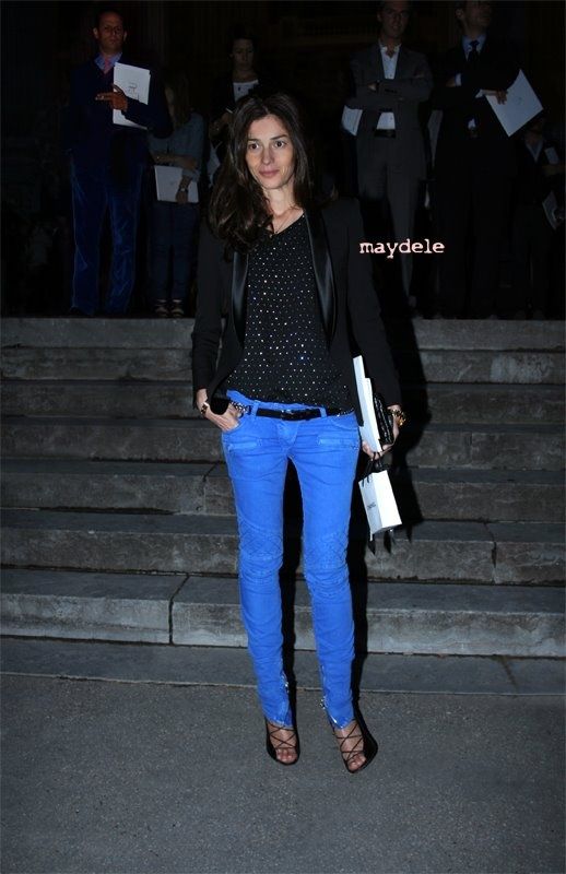 a woman standing in front of some steps wearing blue pants and a black top with polka dots on it