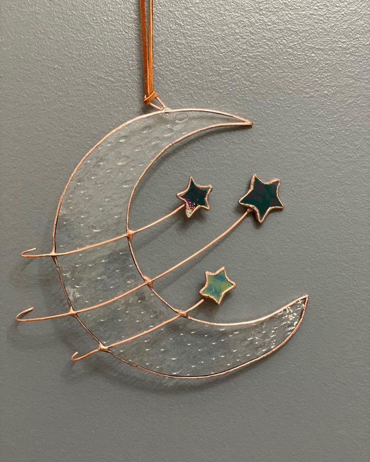 the moon and three stars are hanging from a metal wire holder on a wall ornament