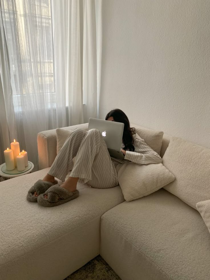 a woman sitting on a couch using a laptop computer