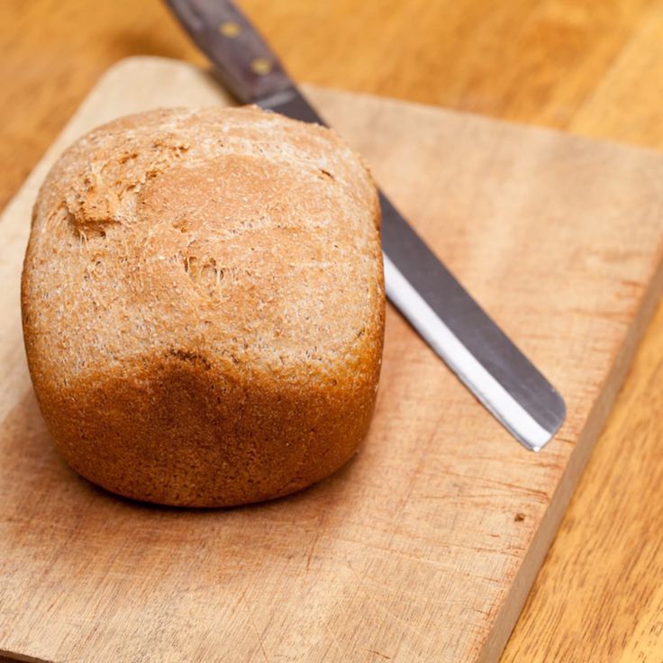 a loaf of bread sitting on top of a wooden cutting board next to a knife