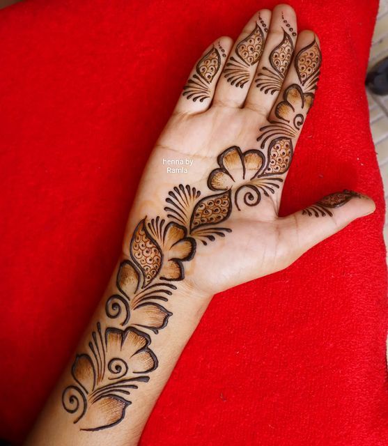 a woman's hand with henna tattoos on her left arm and the top half of