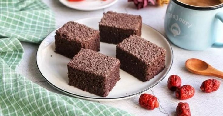 four pieces of brownie on a plate next to raspberries and a cup of coffee