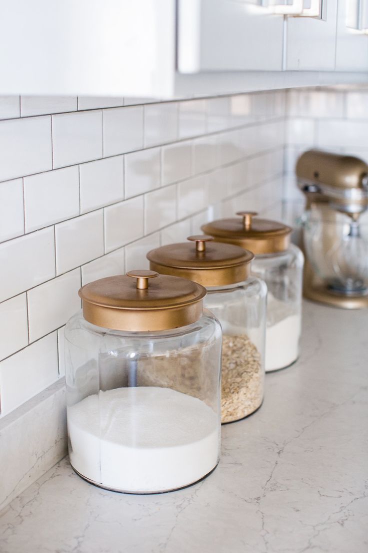 three glass jars filled with different types of food on a kitchen counter next to a coffee grinder