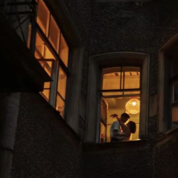 two people standing in an open window at night