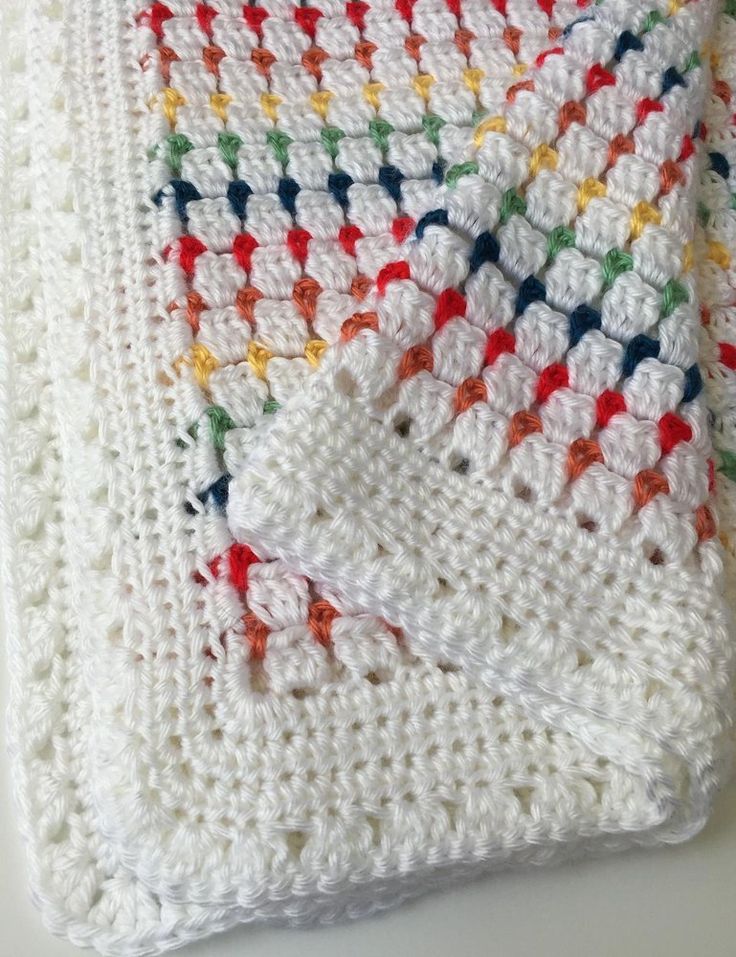 a white crocheted dishcloth with red, yellow, and green squares on it