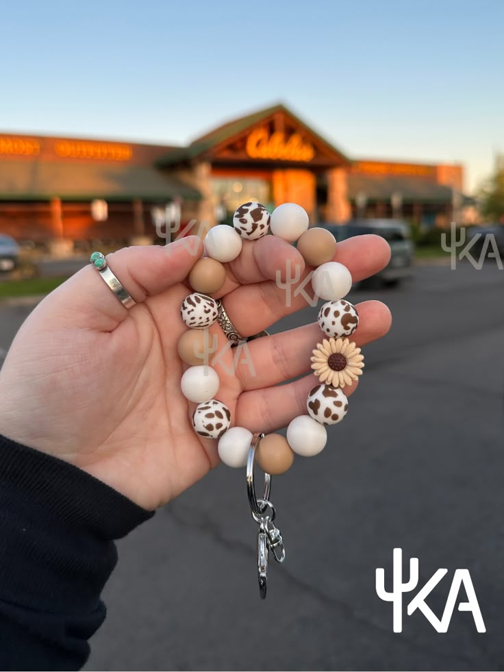 a person holding several bracelets in front of a building with cactus decorations on it