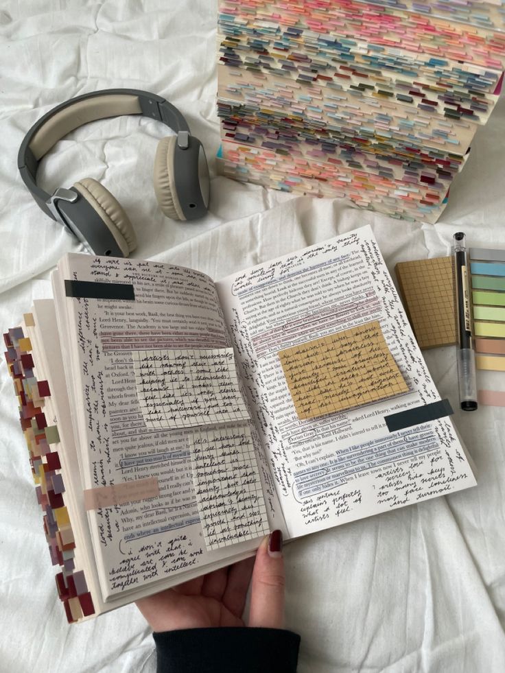 an open book sitting on top of a bed next to headphones