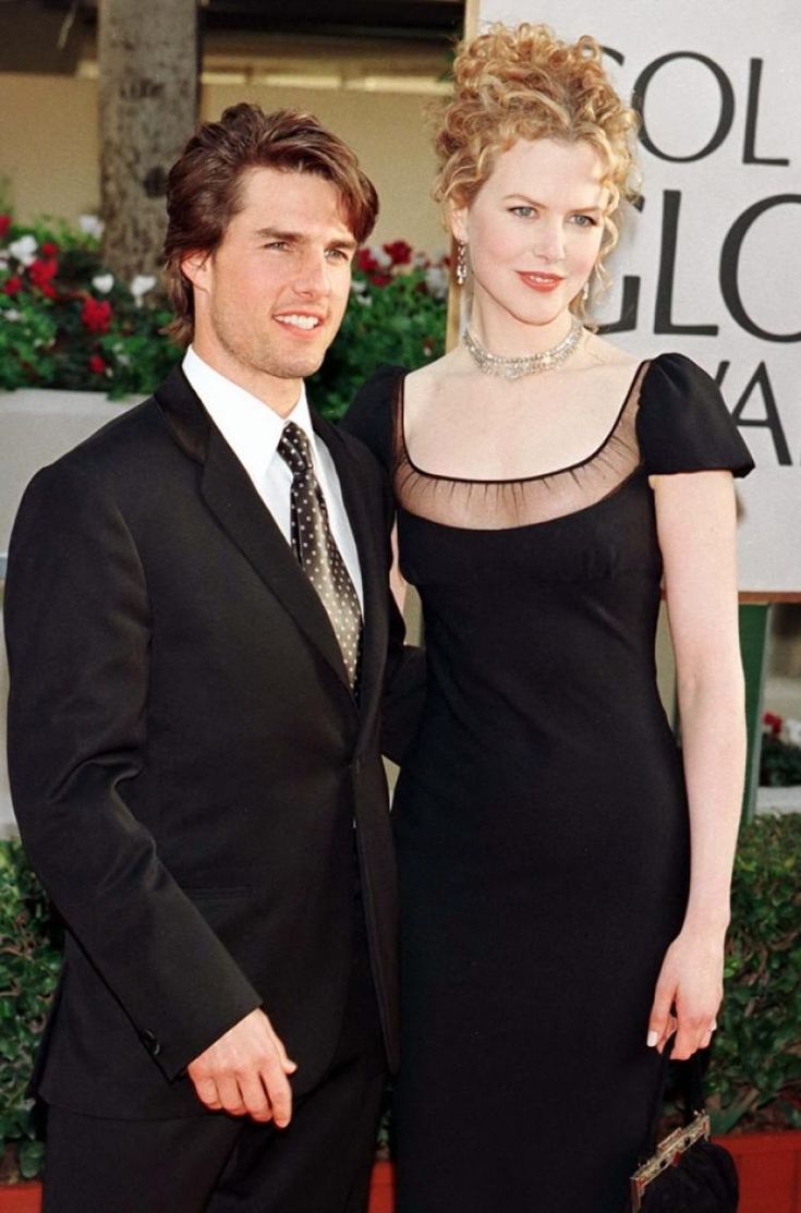 a man and woman standing next to each other on a red carpet