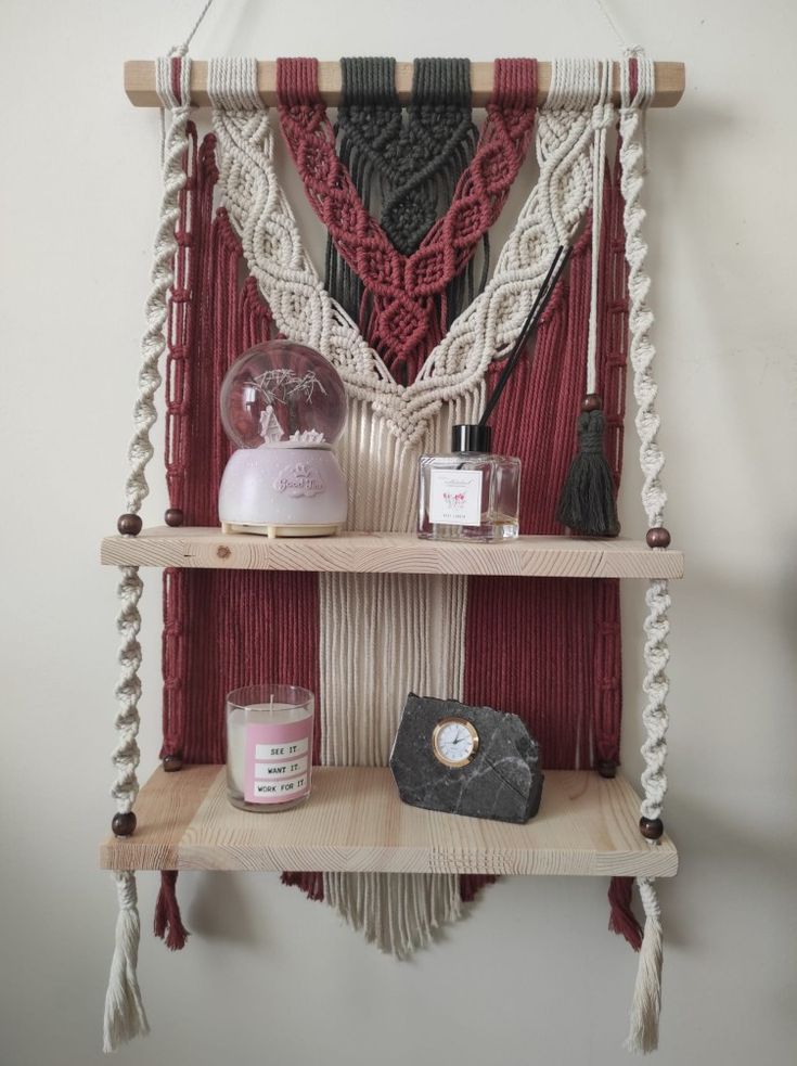 a macrame wall hanging with candles and other items on it in front of a white wall