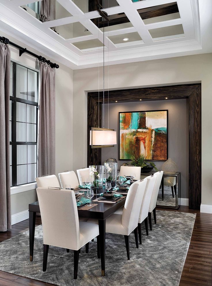 a dining room table with white chairs and a painting on the wall