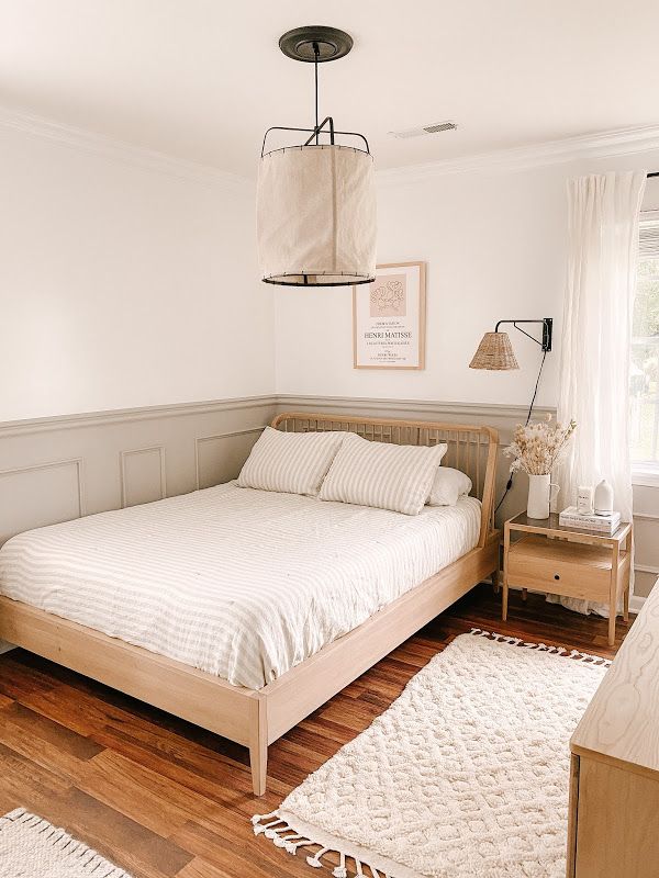 a bed sitting in a bedroom next to a wooden dresser and lamp on top of a hard wood floor