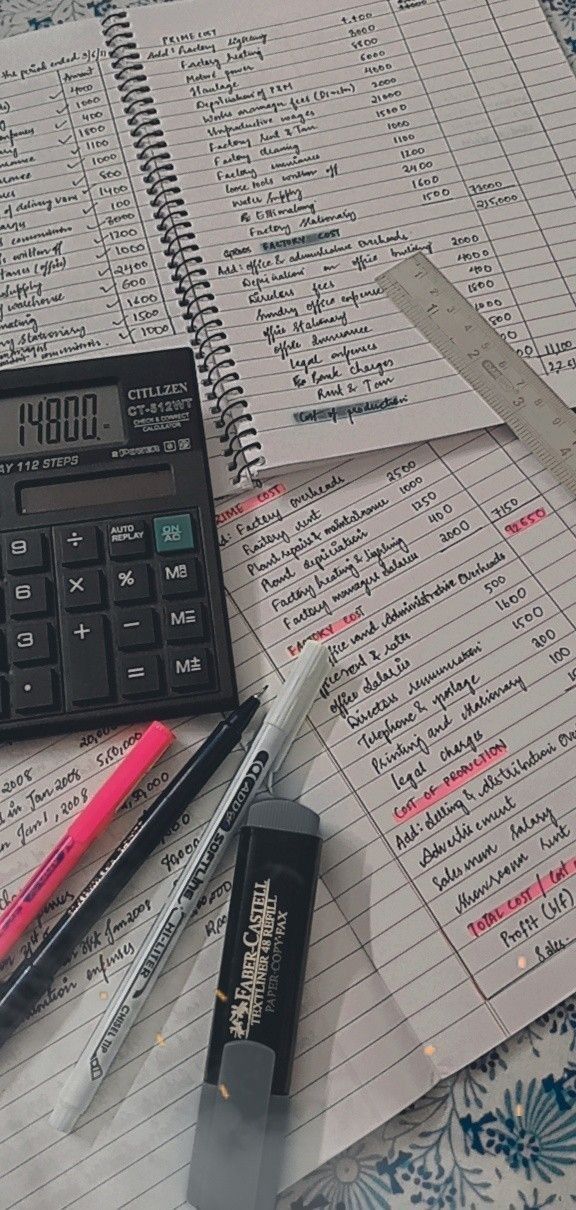 a calculator sitting on top of a table next to some pens and paper