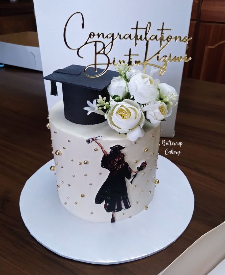 a graduation cake decorated with flowers and an image of a graduate's cap on top