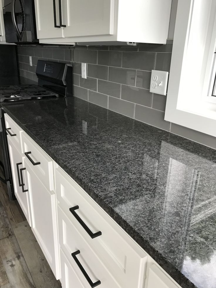 a kitchen counter top with white cabinets and black appliances in the backgroung