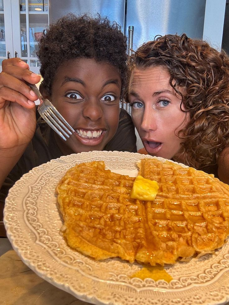 two women are posing with a plate of waffles