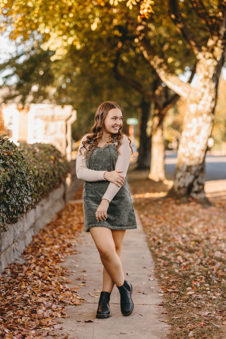 a young woman is walking down the sidewalk in an autumn dress and black booties