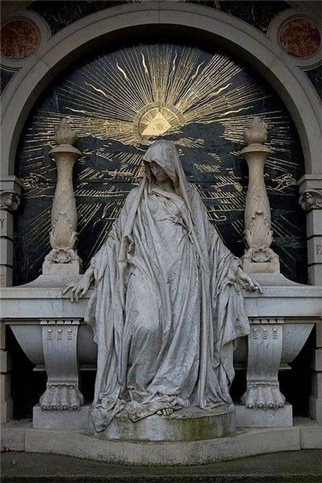 black and white photograph of the statue of mary in front of an ornate arch with sunburst above it