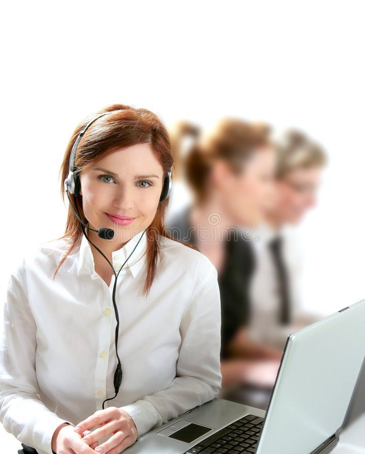 a woman wearing a headset sitting in front of a laptop computer with two other people behind her