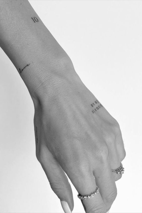 a woman's hand with two small rings on it and the word love is written on her wrist