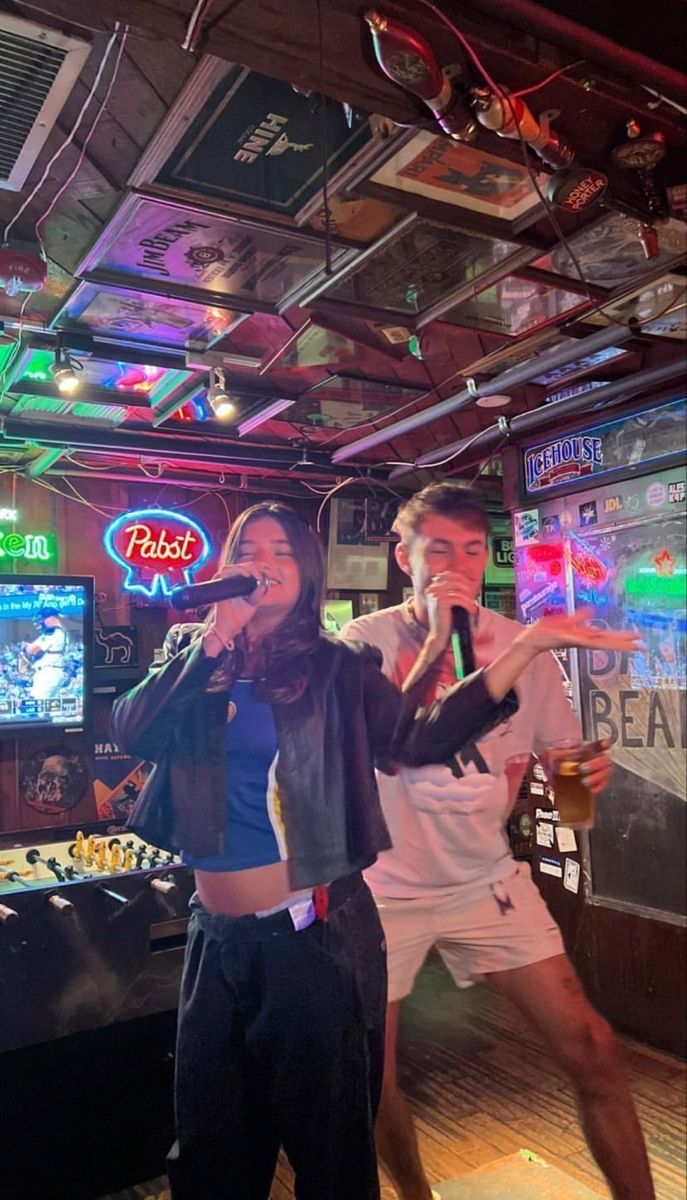 two people singing into microphones in a bar