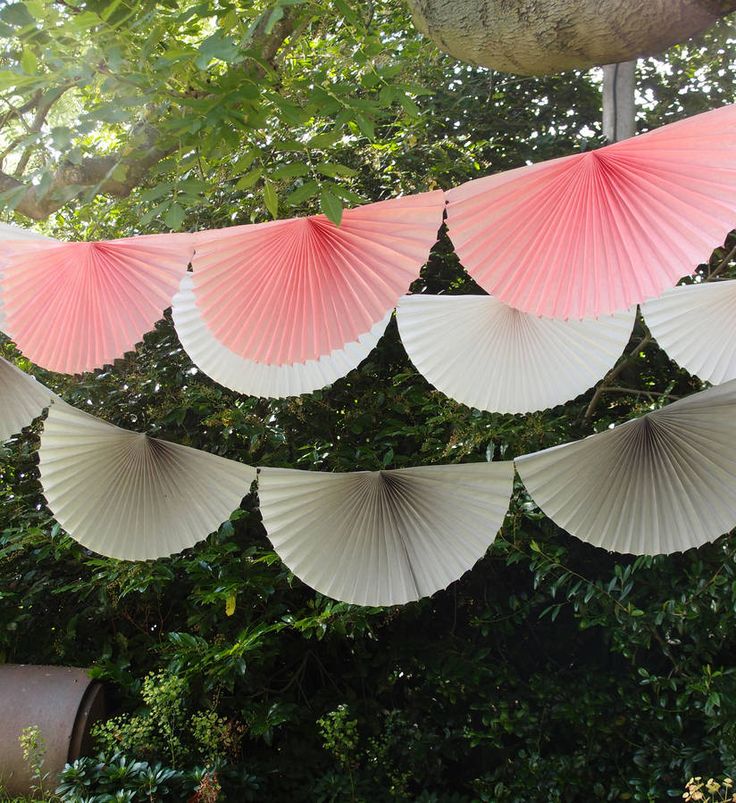 pink and white paper fans hanging from a tree