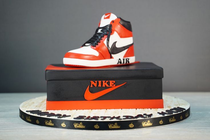 a pair of nike sneakers sitting on top of a shoe box that is decorated with black, orange and white