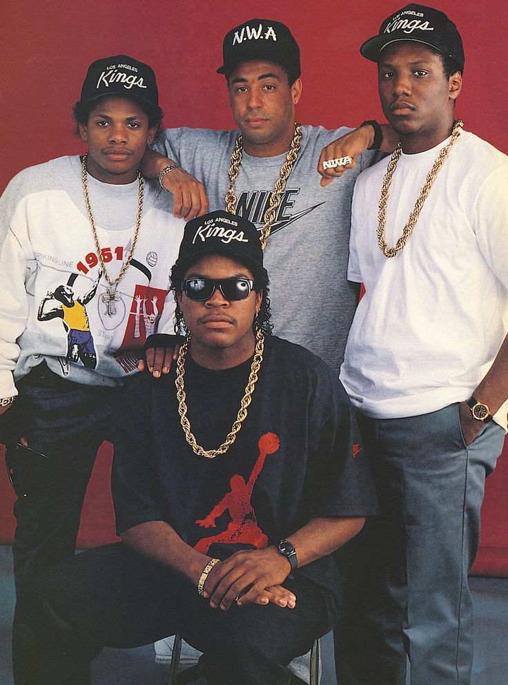 four young men posing for a photo in front of a red wall with chains on them