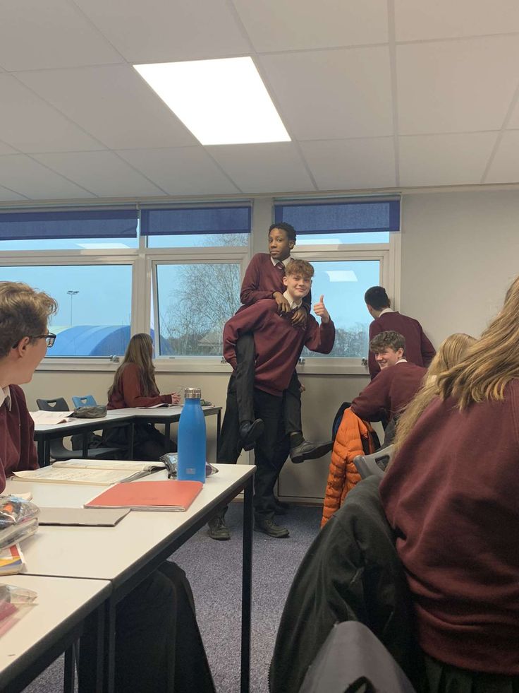 some students are sitting at their desks and one boy is holding something in his hand