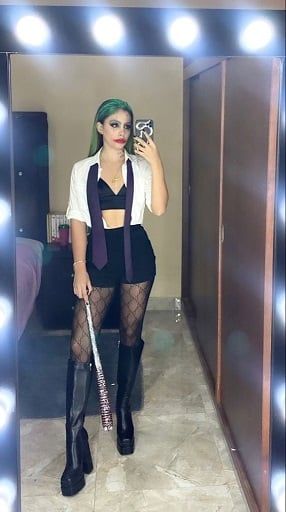 a woman with green hair is taking a selfie in front of a lighted mirror