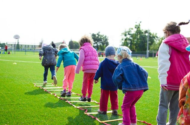 a group of people standing on top of a green field next to a line of skis