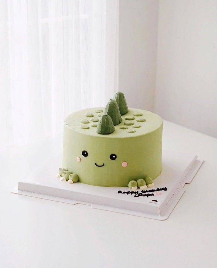 a green cake sitting on top of a white table