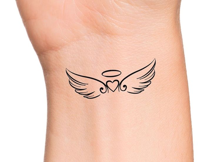 a woman's wrist with an angel wing tattoo on the left side of her arm