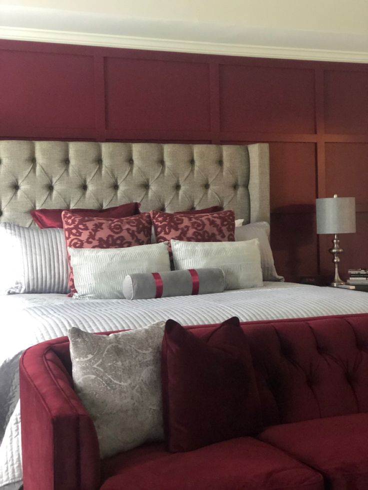 a large bed sitting in the middle of a bedroom next to a red couch and lamp