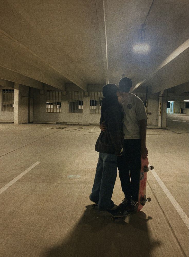 two people standing in an empty parking garage with their skateboards on the ground,