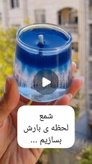 a person holding up a blue candle in front of a building with the words written in arabic