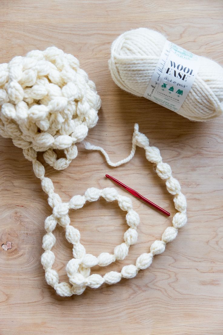 two balls of yarn sitting on top of a wooden table next to a ball of yarn