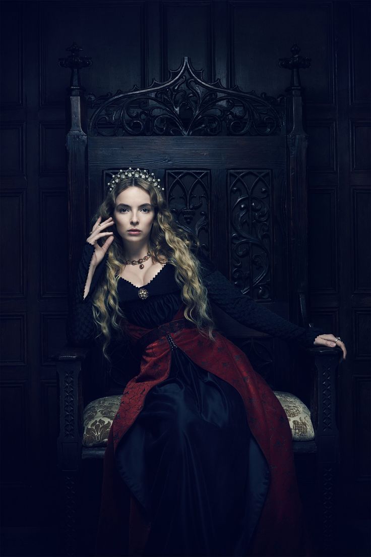 a woman with long blonde hair sitting on a chair in a black and red dress