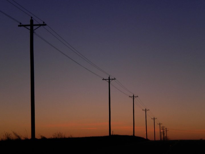 power lines and telephone poles silhouetted against the evening sky