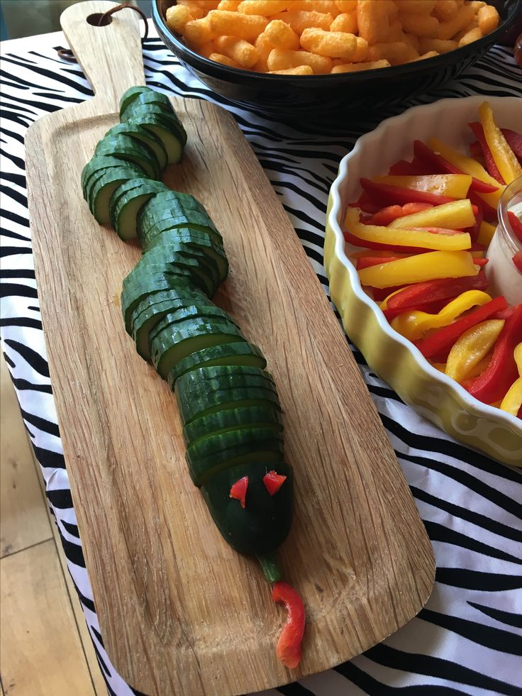 a caterpillar shaped like a snake on a cutting board next to other foods