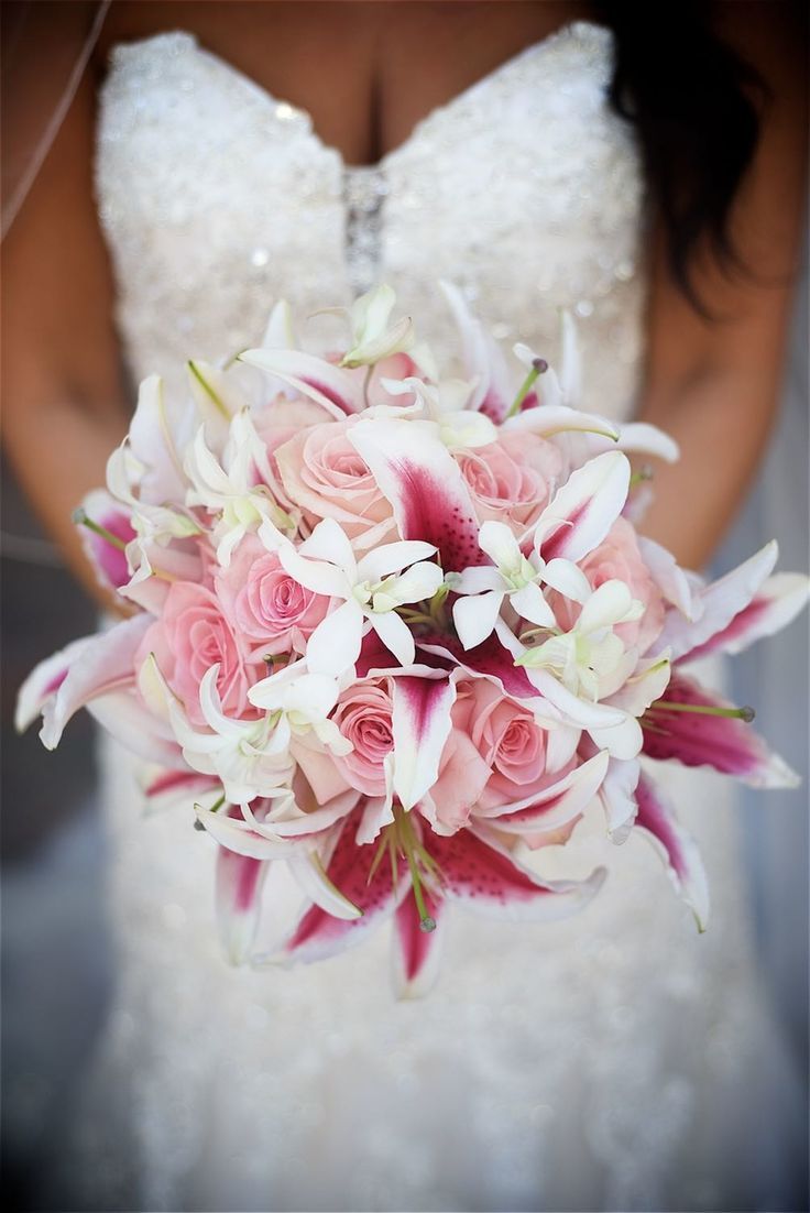 a bridal holding a bouquet of pink roses and white lilies in her hands