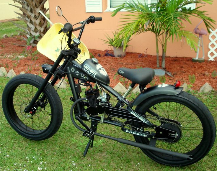 a black motorcycle parked on top of a green grass covered field next to a house