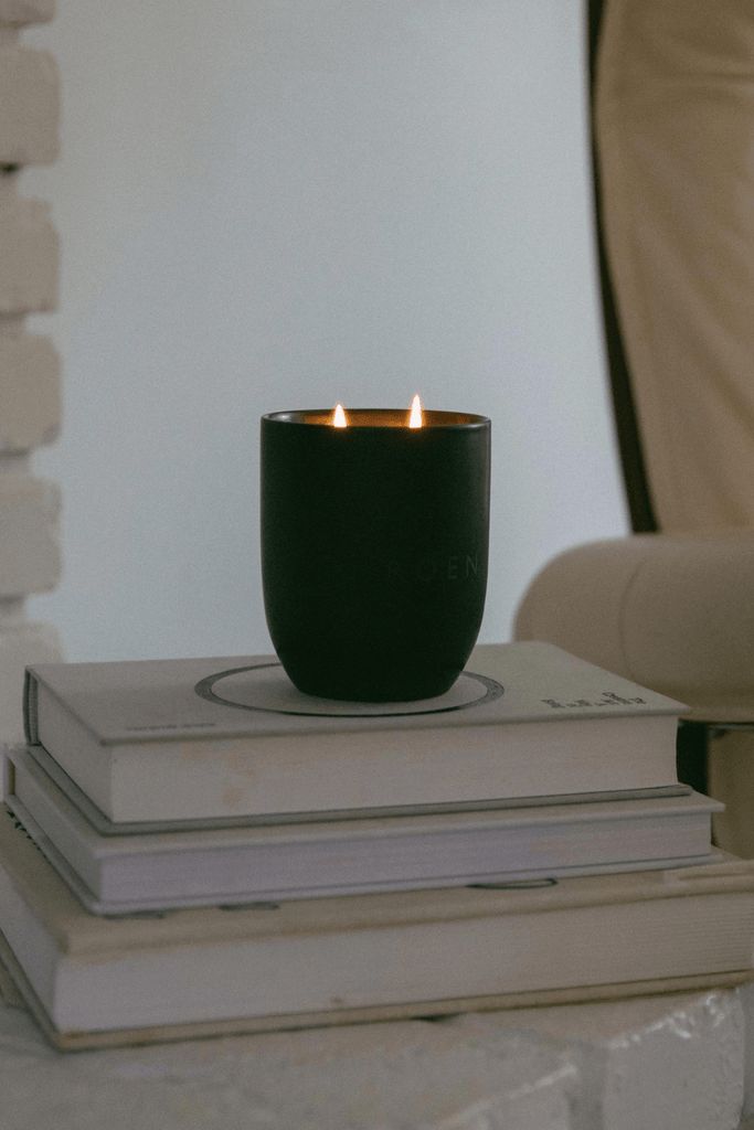 a lit candle sitting on top of two stacked books in front of a white wall