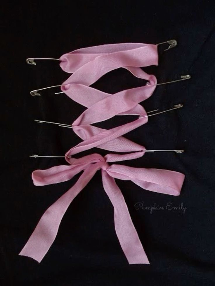 pink ribbon and pins on black background