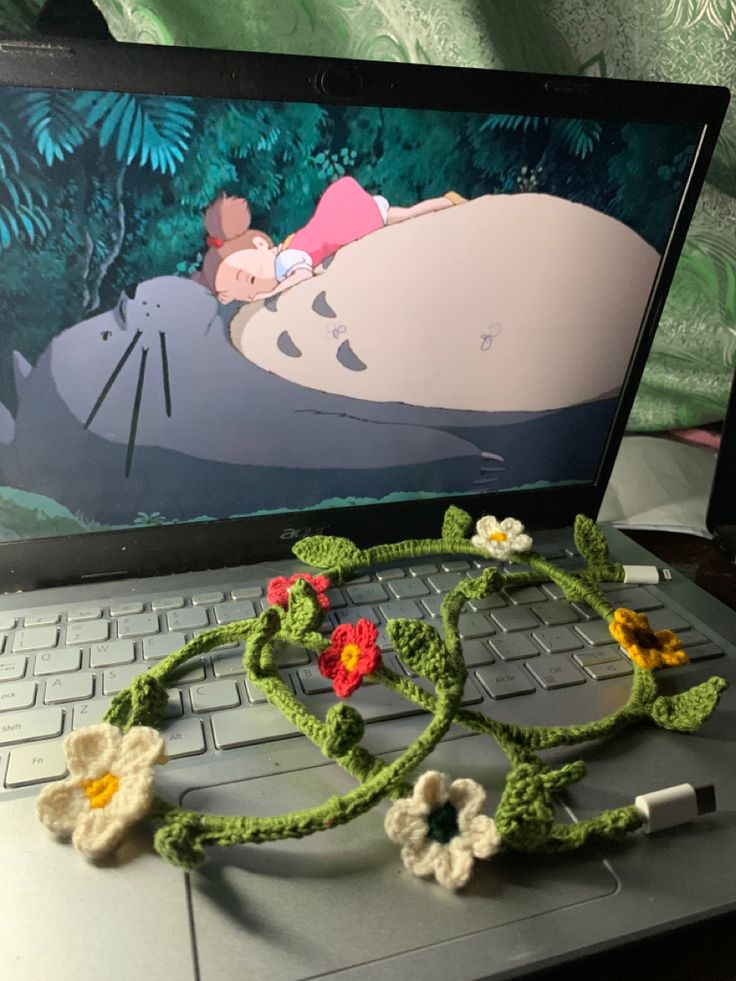 a crocheted necklace laying on top of an open laptop computer with the image of a sleeping hippo