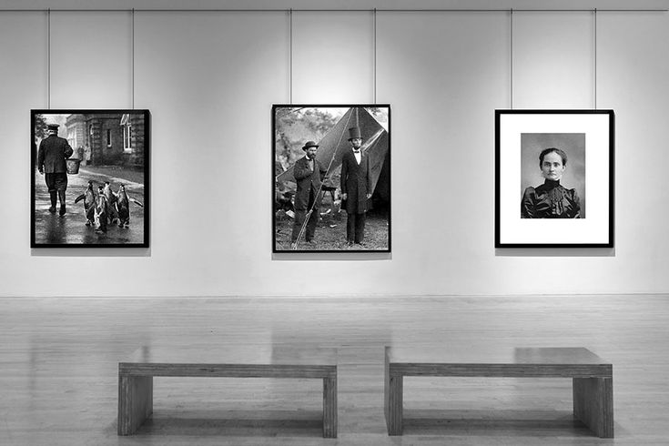 four black and white photographs hang on the wall in an art gallery with benches underneath them