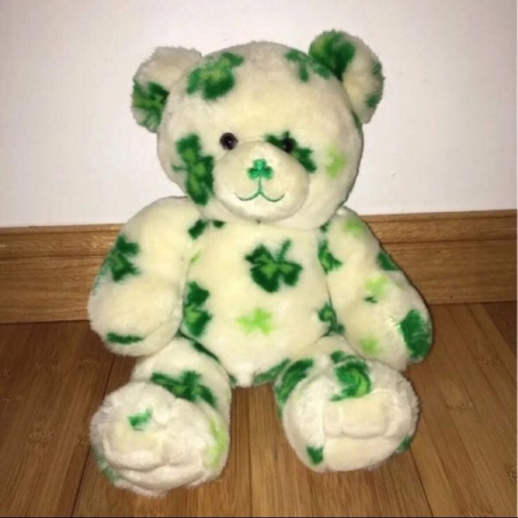 a green and white teddy bear sitting on the floor