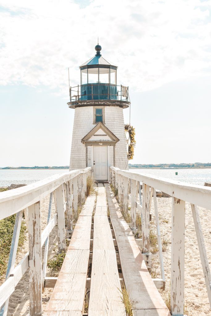 a light house sitting on top of a sandy beach next to the ocean with stairs leading up to it